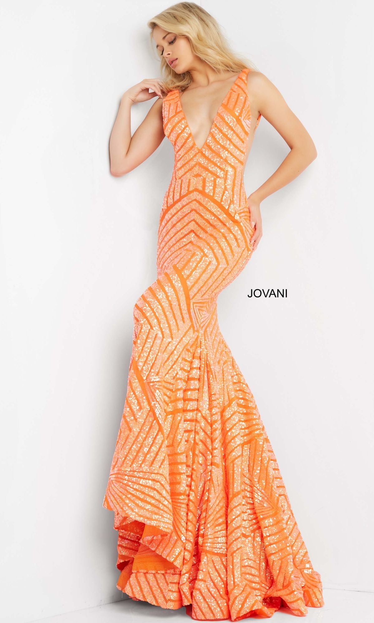 A woman in a sleeveless v-neck Jovani Prom Dress with an orange striped sequin pattern stands against a white background, with the Jovani brand name visible on the gown.